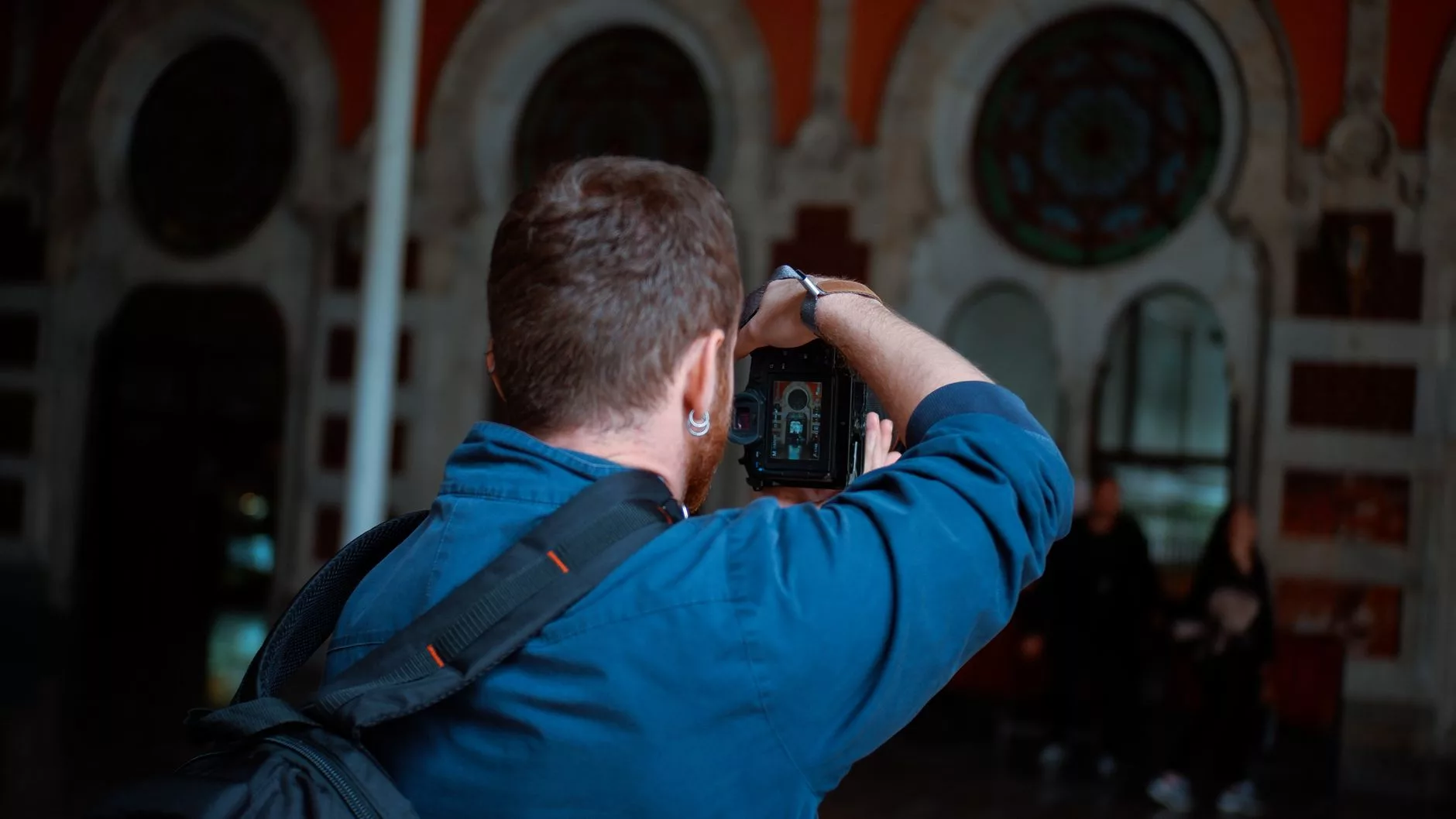 Eski bir meydanda elinde küçük bir fotoğraf makinesiyle fotoğraf çeken bir gezgin