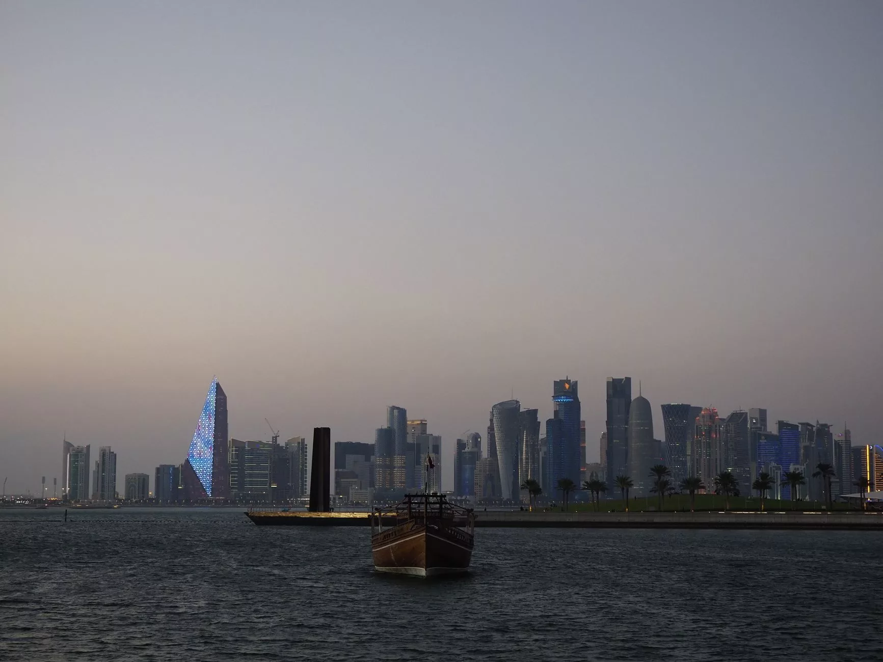 Doha – modern gökdelenlerin ve geleneksel dhow teknelerinin bir arada olduğu gün batımı manzarası