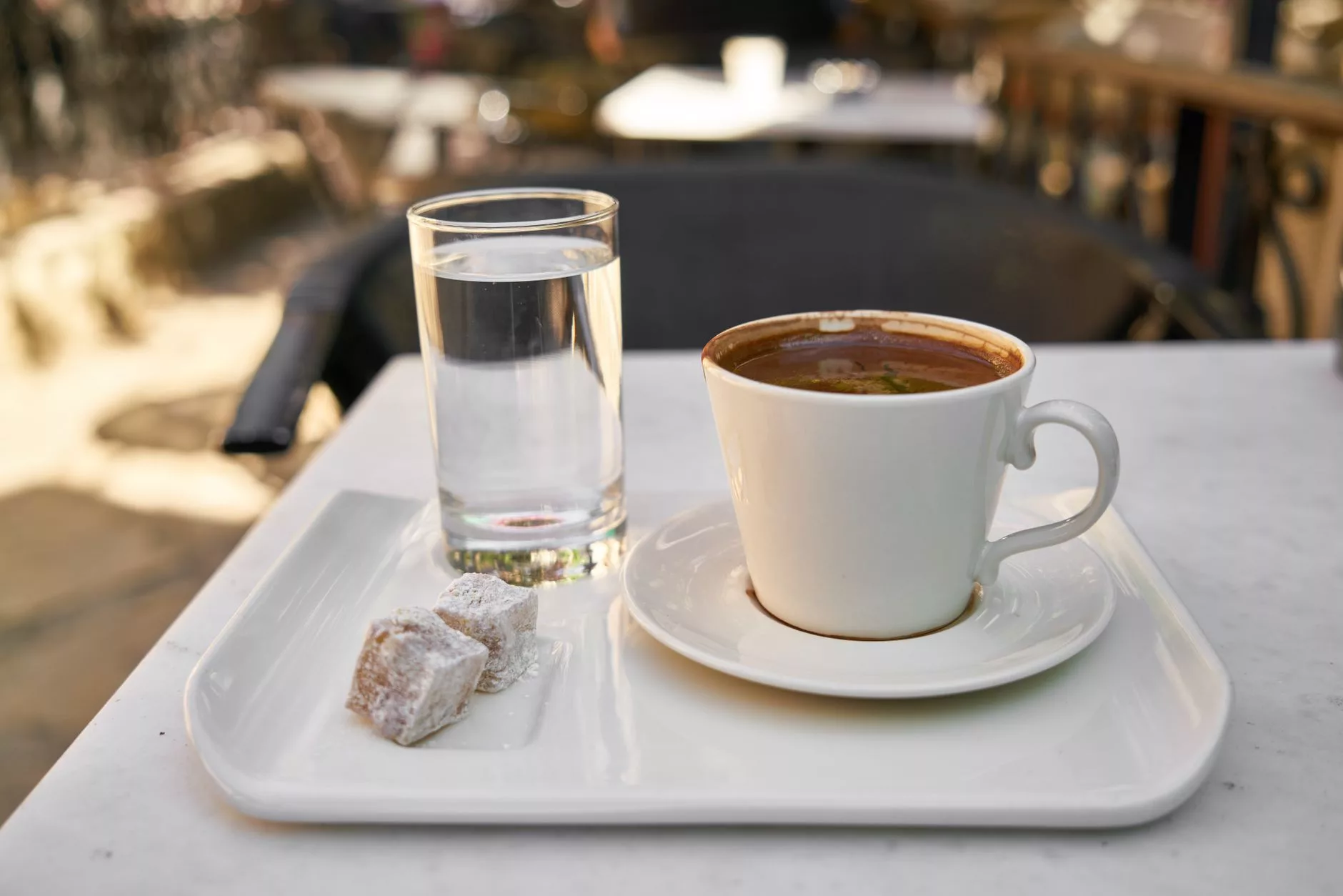 Atina sokaklarında Akropolis manzarasına bakan kalabalık bir kafe ve Türk kahvesi sipariş eden gezginler