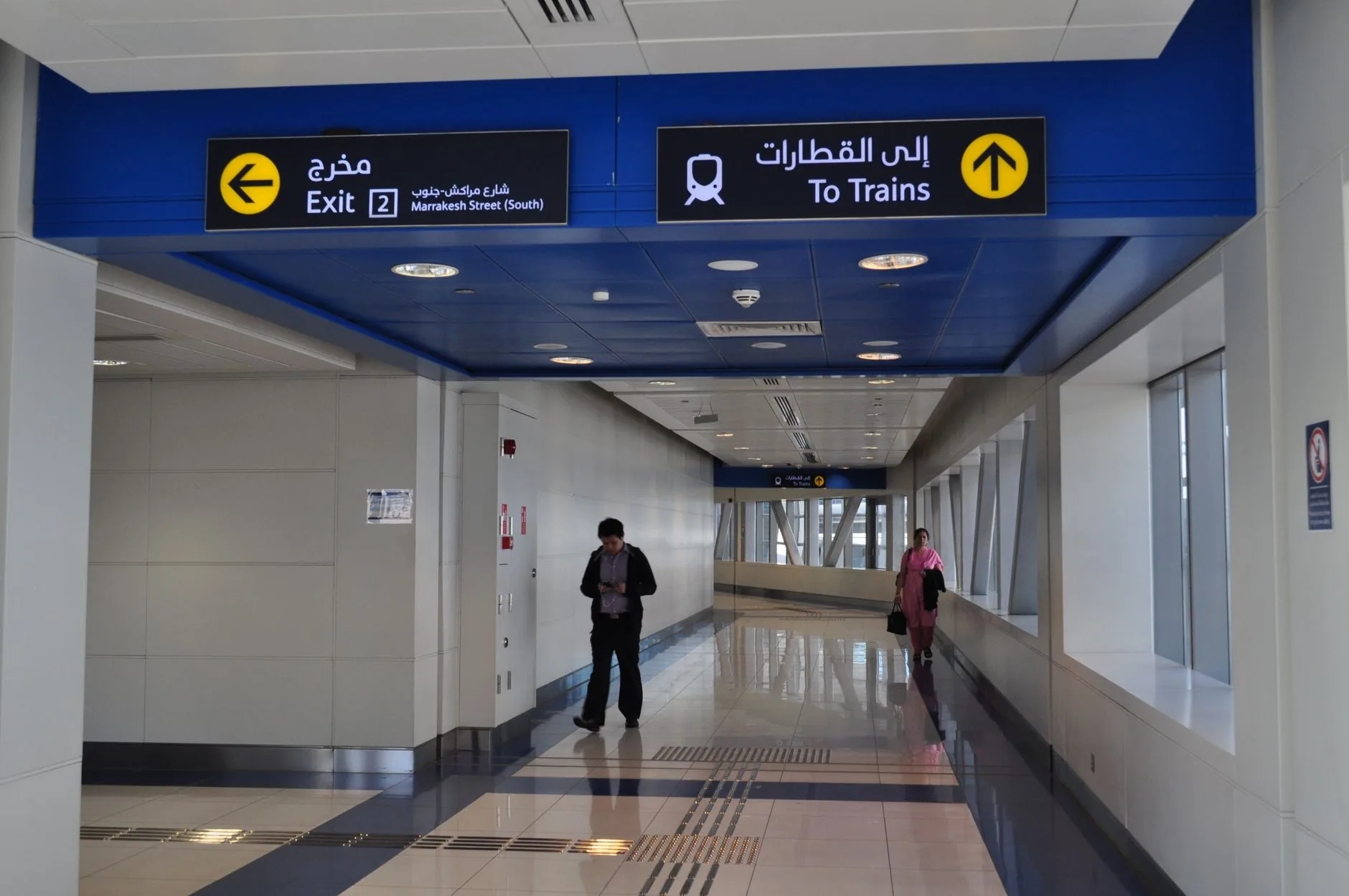 Dubai Metro istasyonunda turist yön tabelaları ve kalabalık peronda yerel sakinler