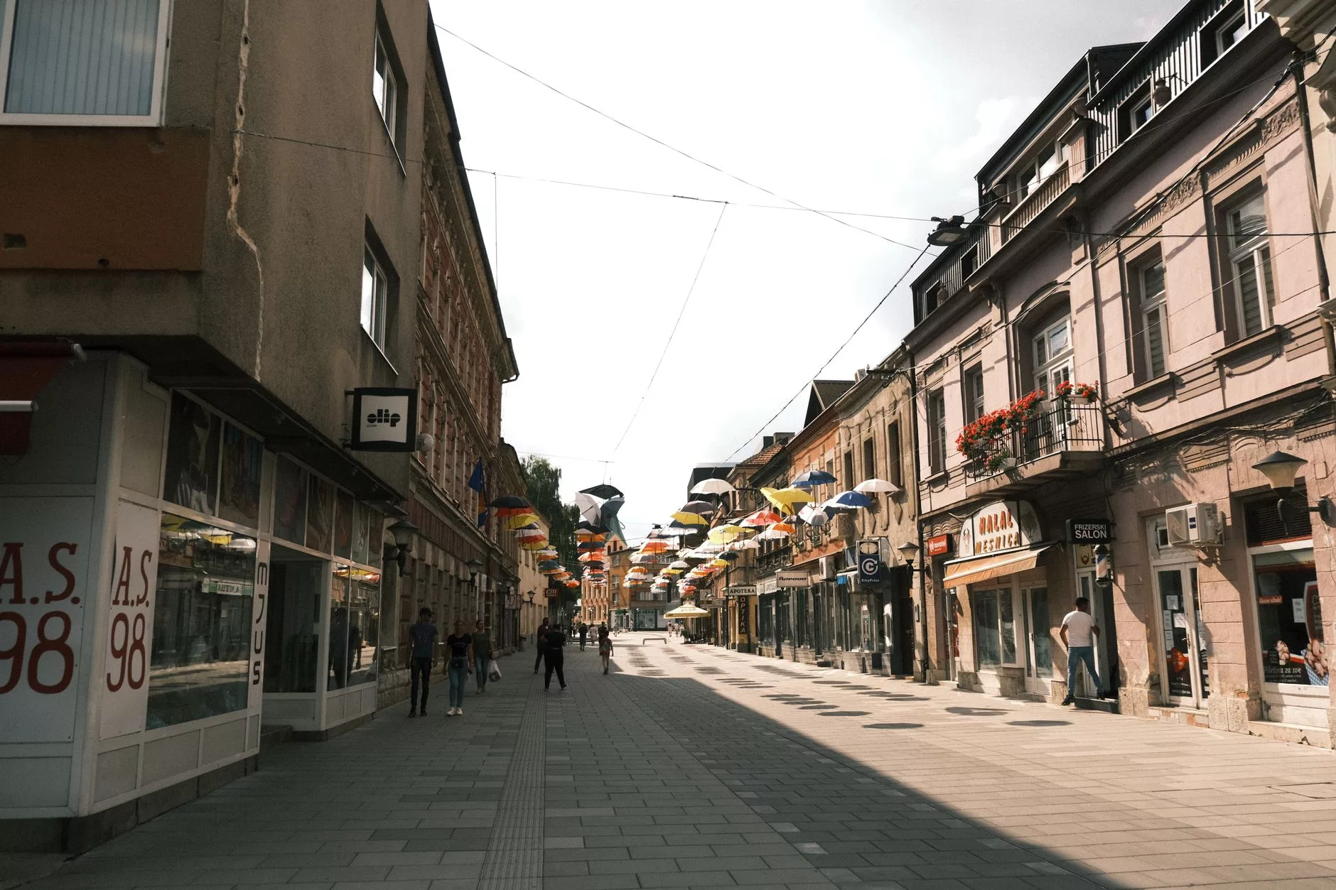 Saraybosna'nın dar sokaklarında eski dükkanların arasından geçen insanlar