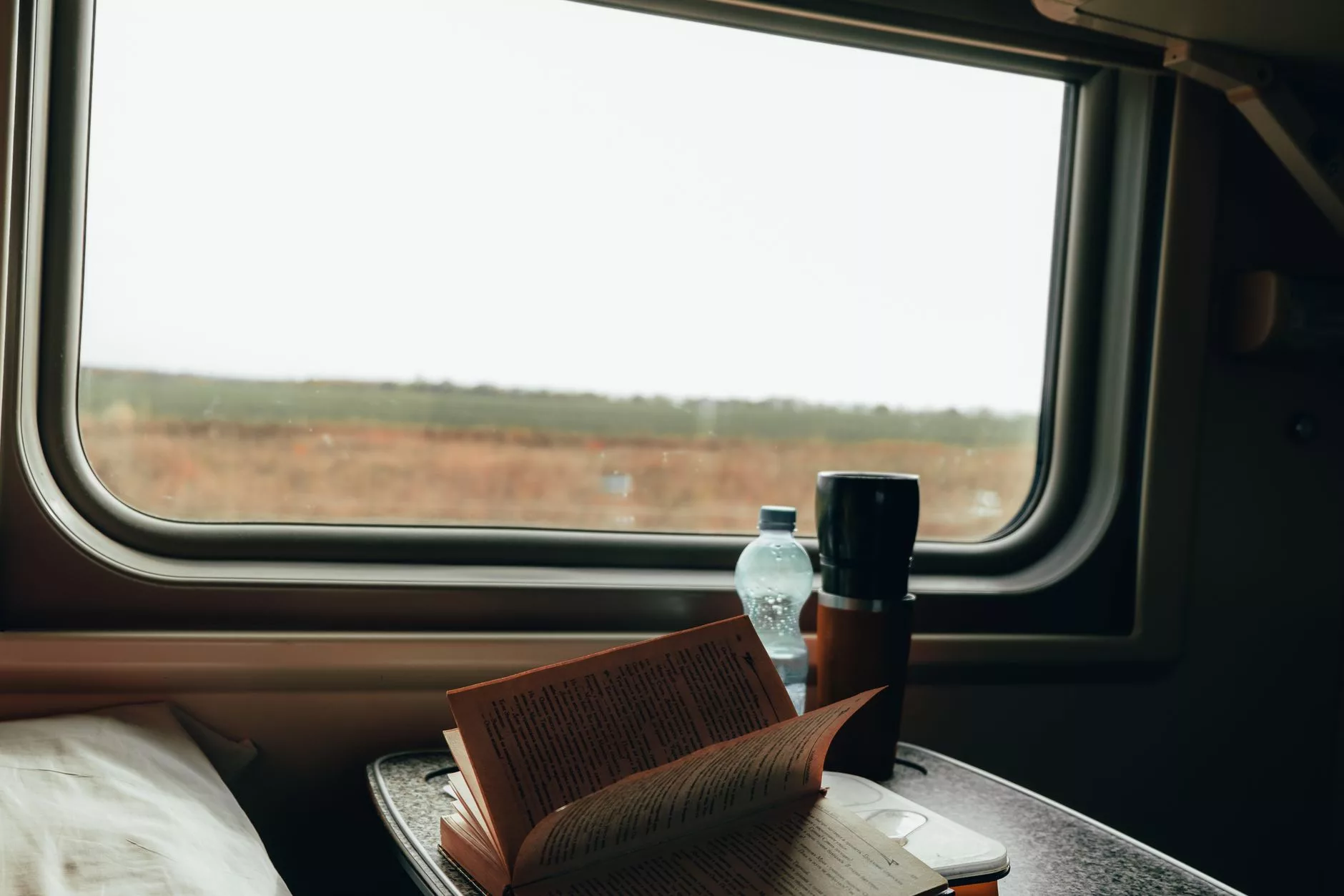 Tren koltuğunda açık bir sırt çantası ve kitap
