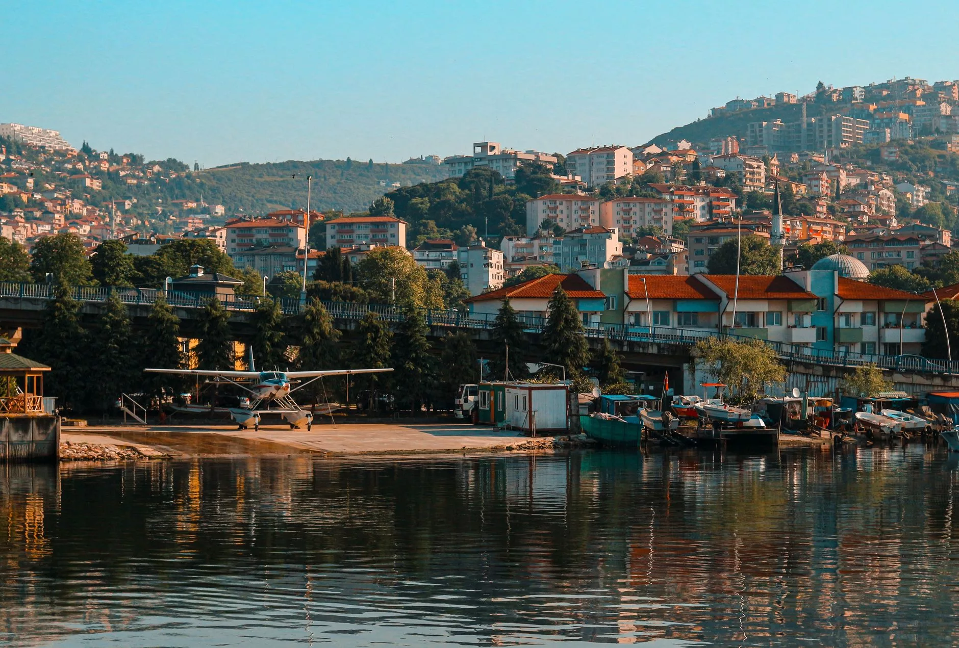 Tivat körfezinin masmavi suları üzerinde alçalan bir uçak penceresinden sahil şeridi ve dağ manzarası