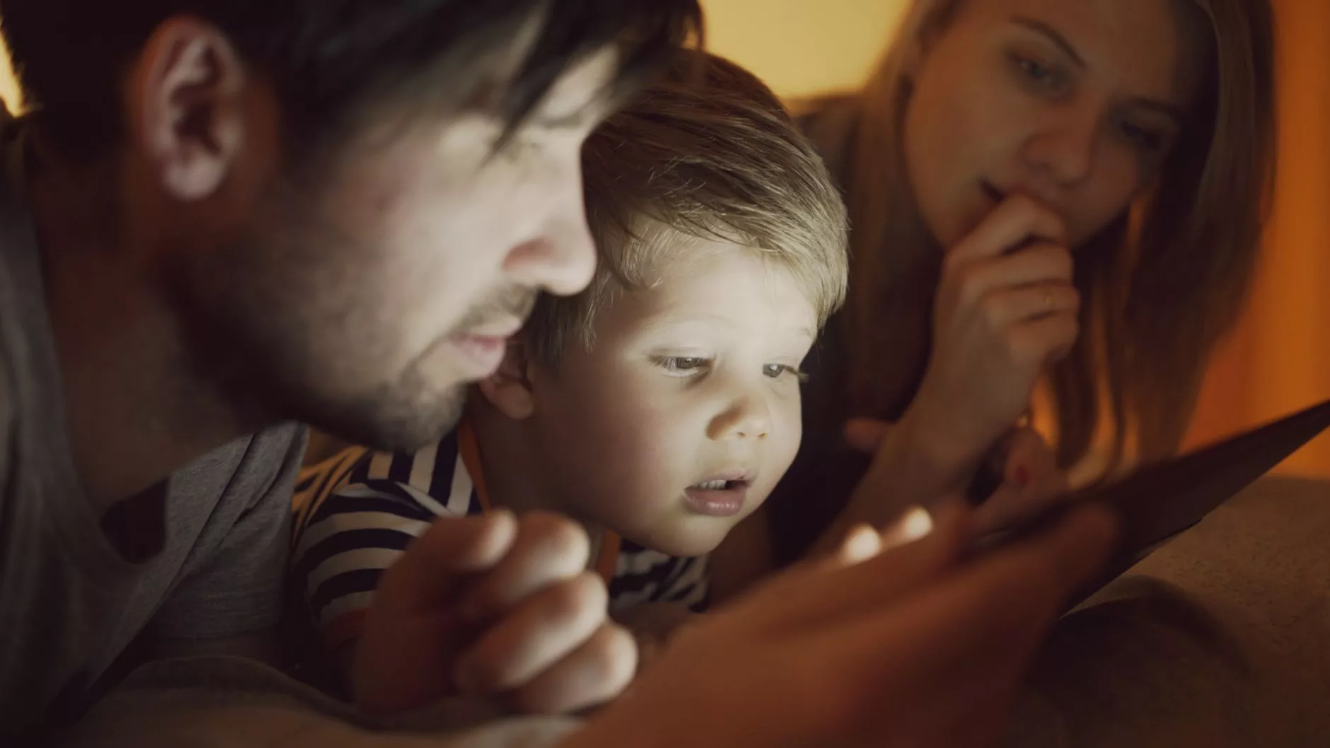 Tablet izleyen çocuk ve rahatlamış bir ebeveyn
