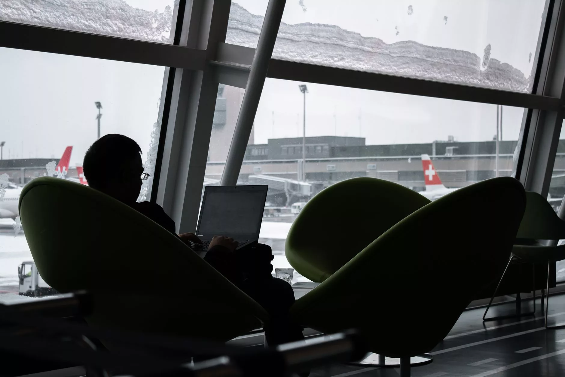 Havalimanı lounge alanında rahatça oturan ve bilgisayarında çalışan bir gezgin
