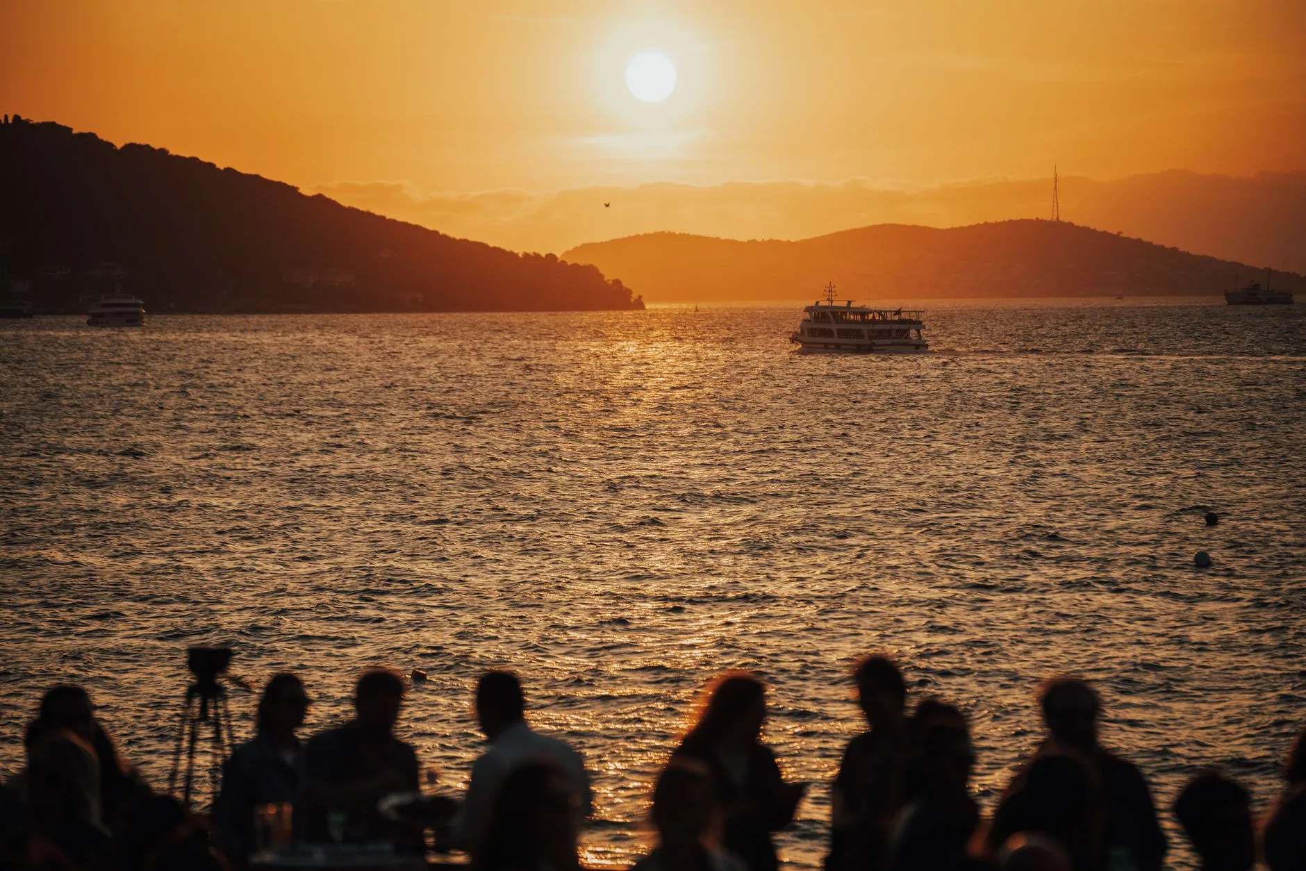 kalabalık bir sahil şeridi, arkada gün batımı