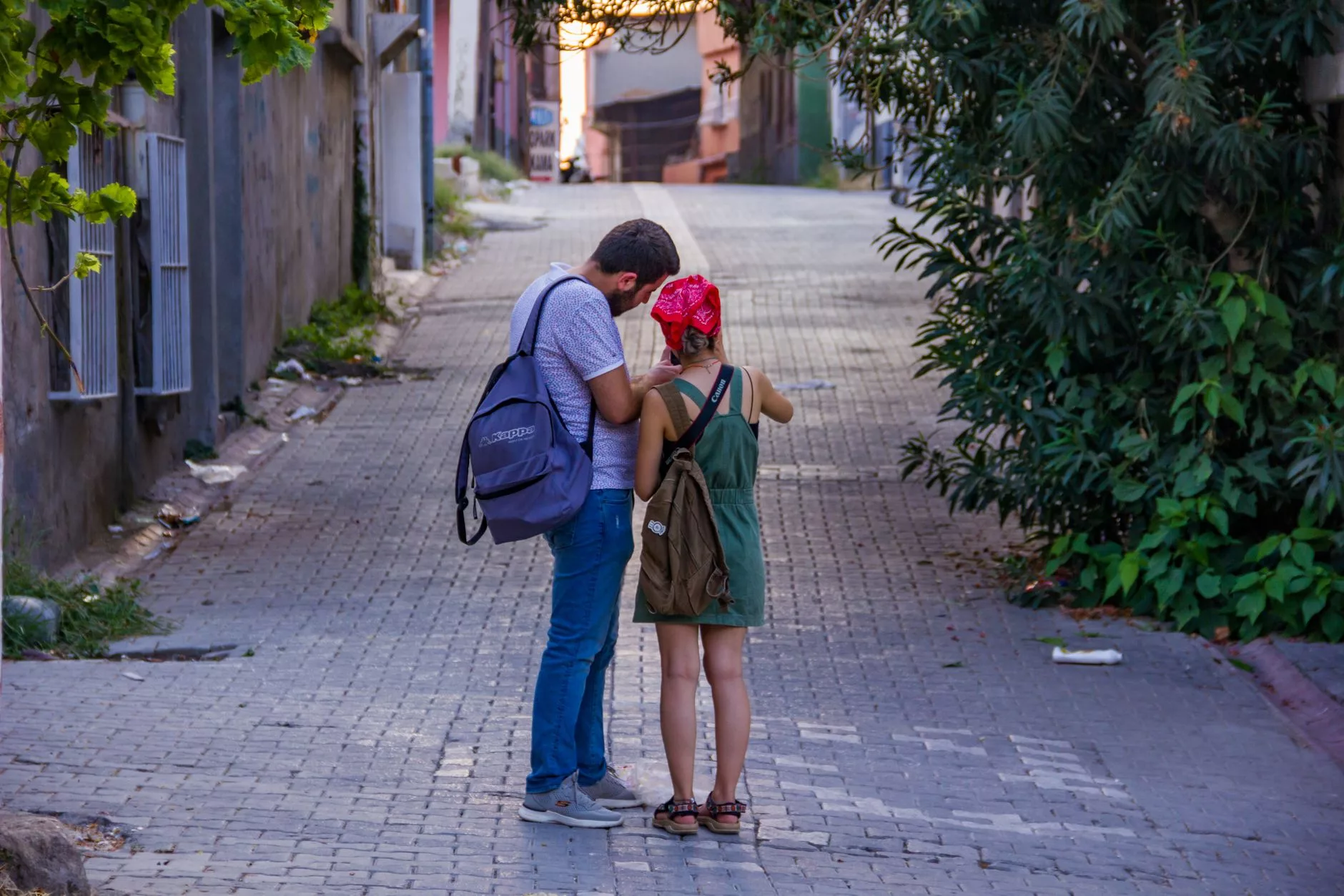 sırt çantalı bir kişi haritaya bakarak eski bir sokakta yürüyor