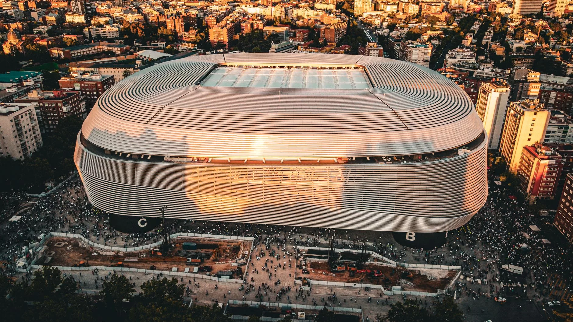 Santiago Bernabeu stadyumu önünde futbol atkılarıyla poz veren coşkulu taraftarlar
