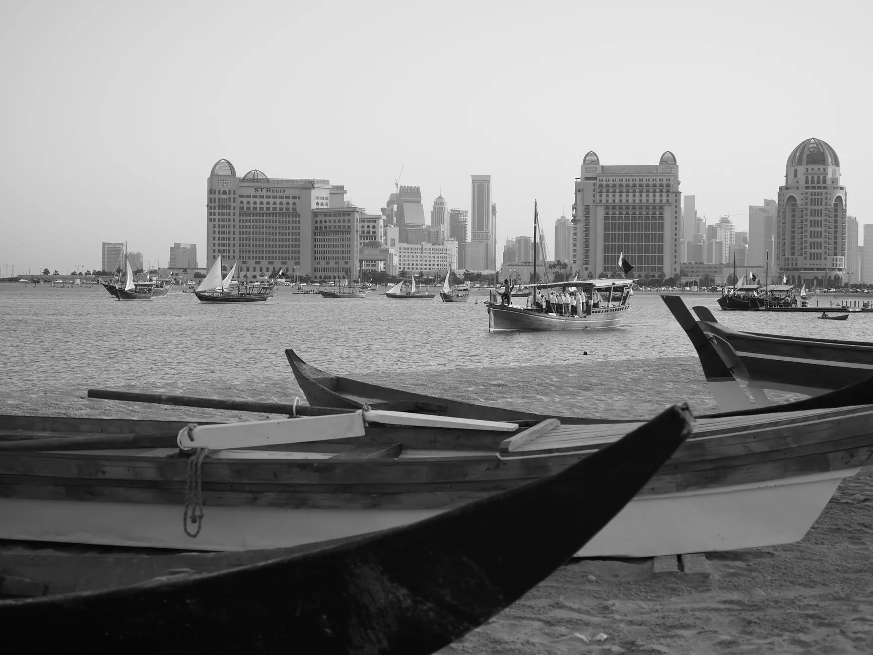 Modern Doha silüeti ve geleneksel dhow teknelerinin yan yana olduğu sahil şeridi