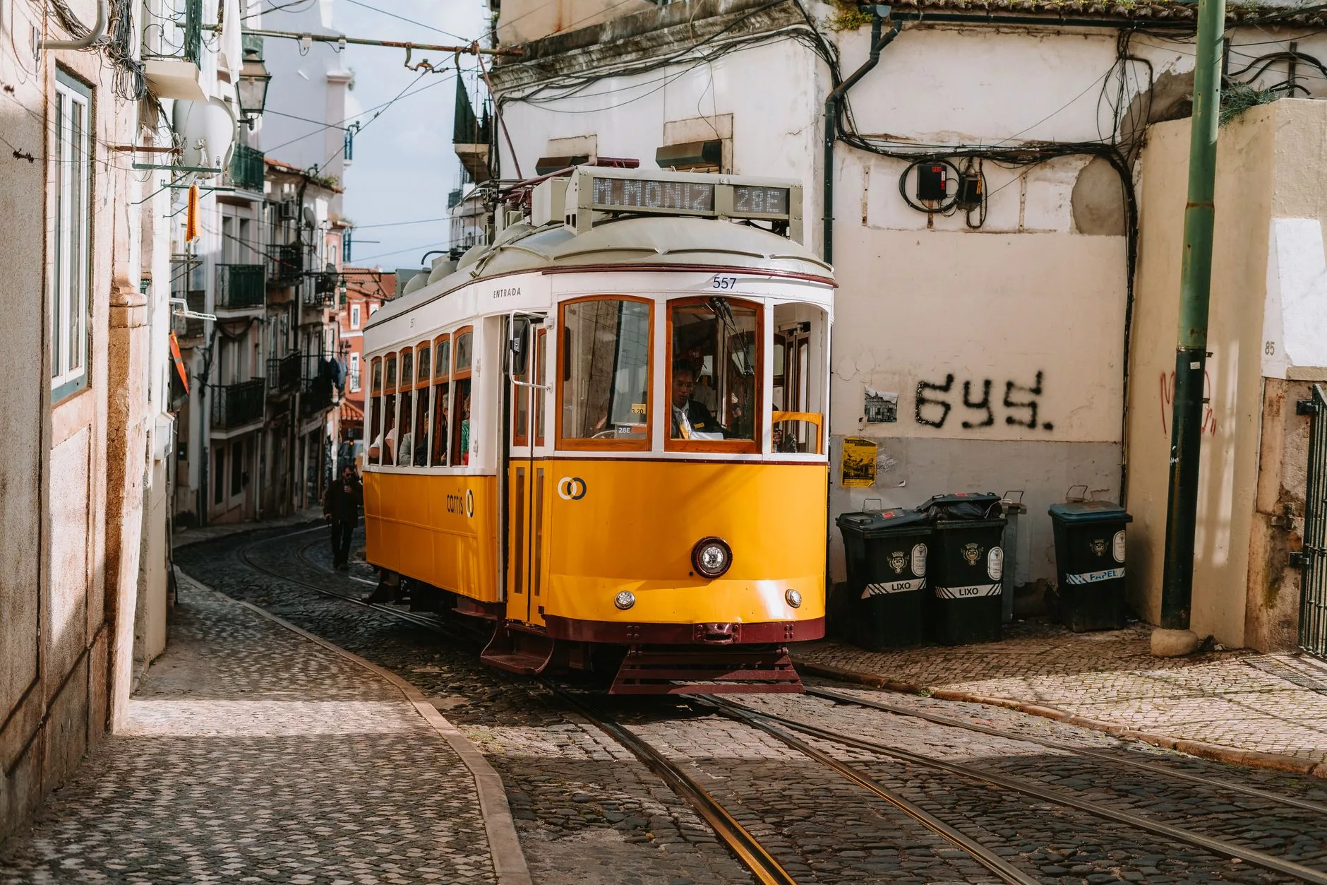 Lizbon + Alfama bölgesinde sarı bir tramvay ve dar sokaklar