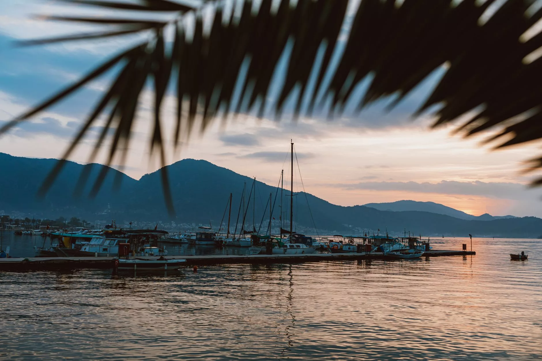 Tropikal bir plajda gün batımı ve ahşap tekneler