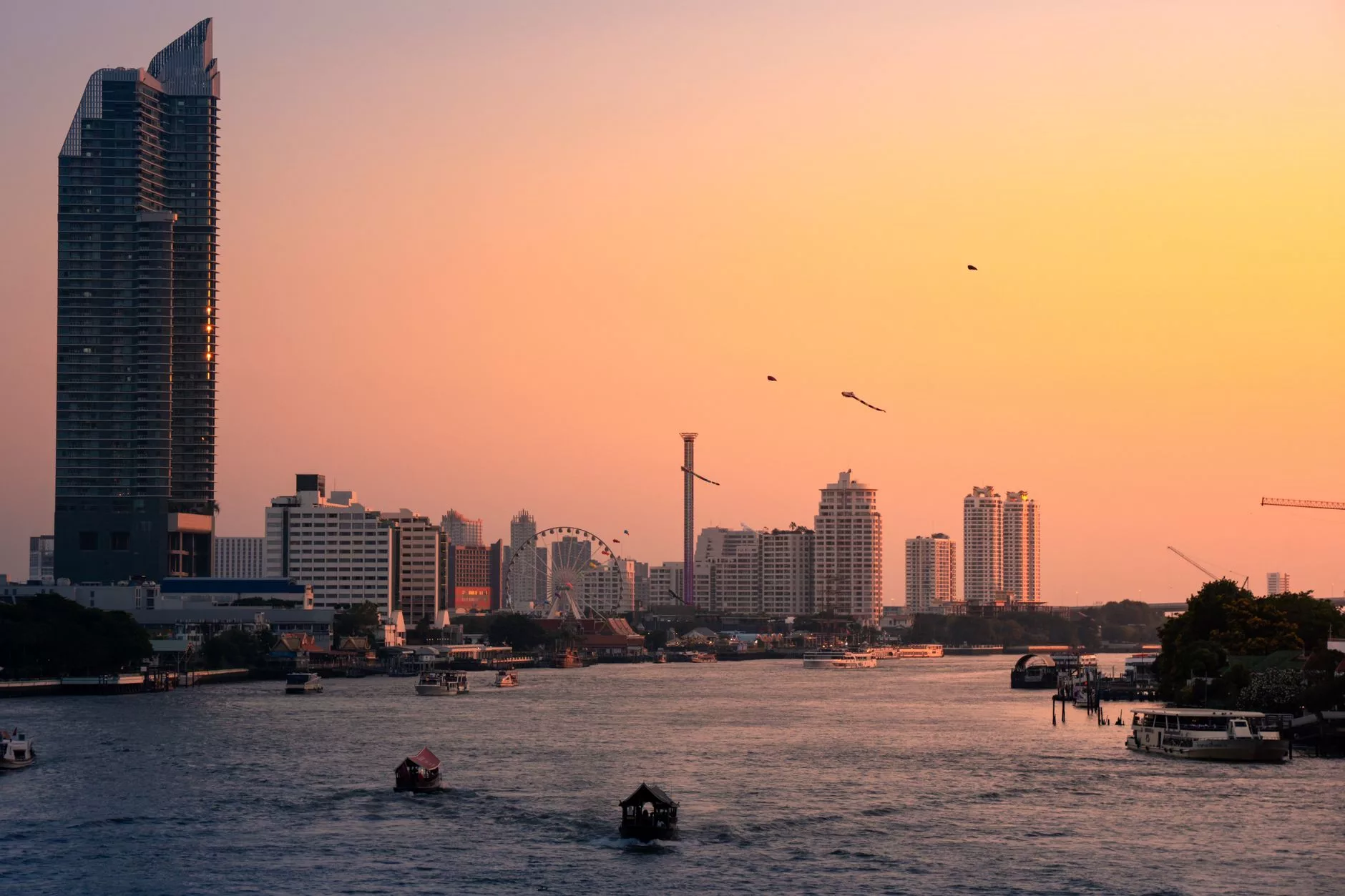 Bangkok Chao Phraya nehri üzerinde gün batımı esnasında hareket eden geleneksel uzun kuyruklu tekneler