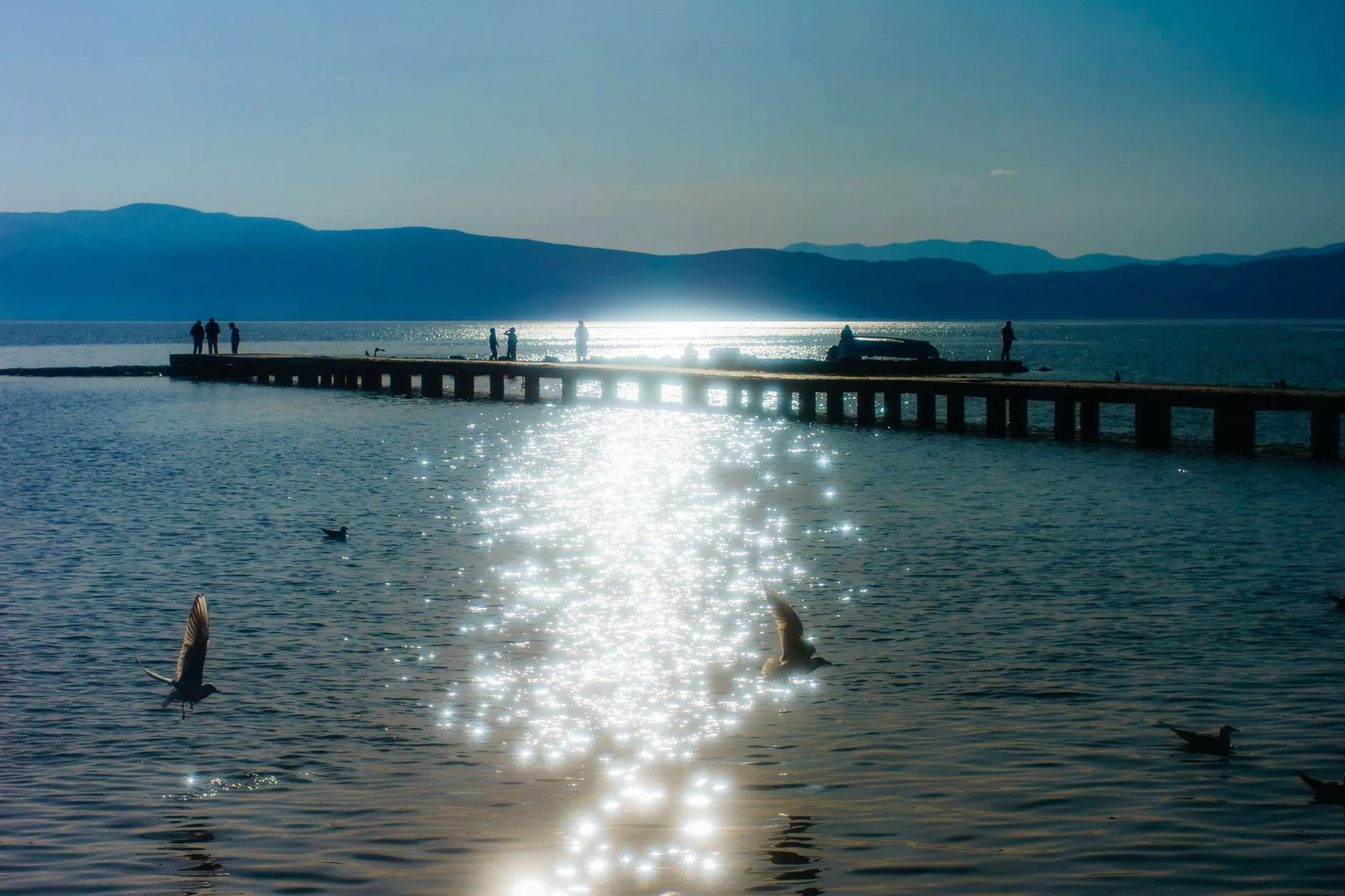Ohrid Gölü üzerinde gün batımı ve ahşap iskeleler