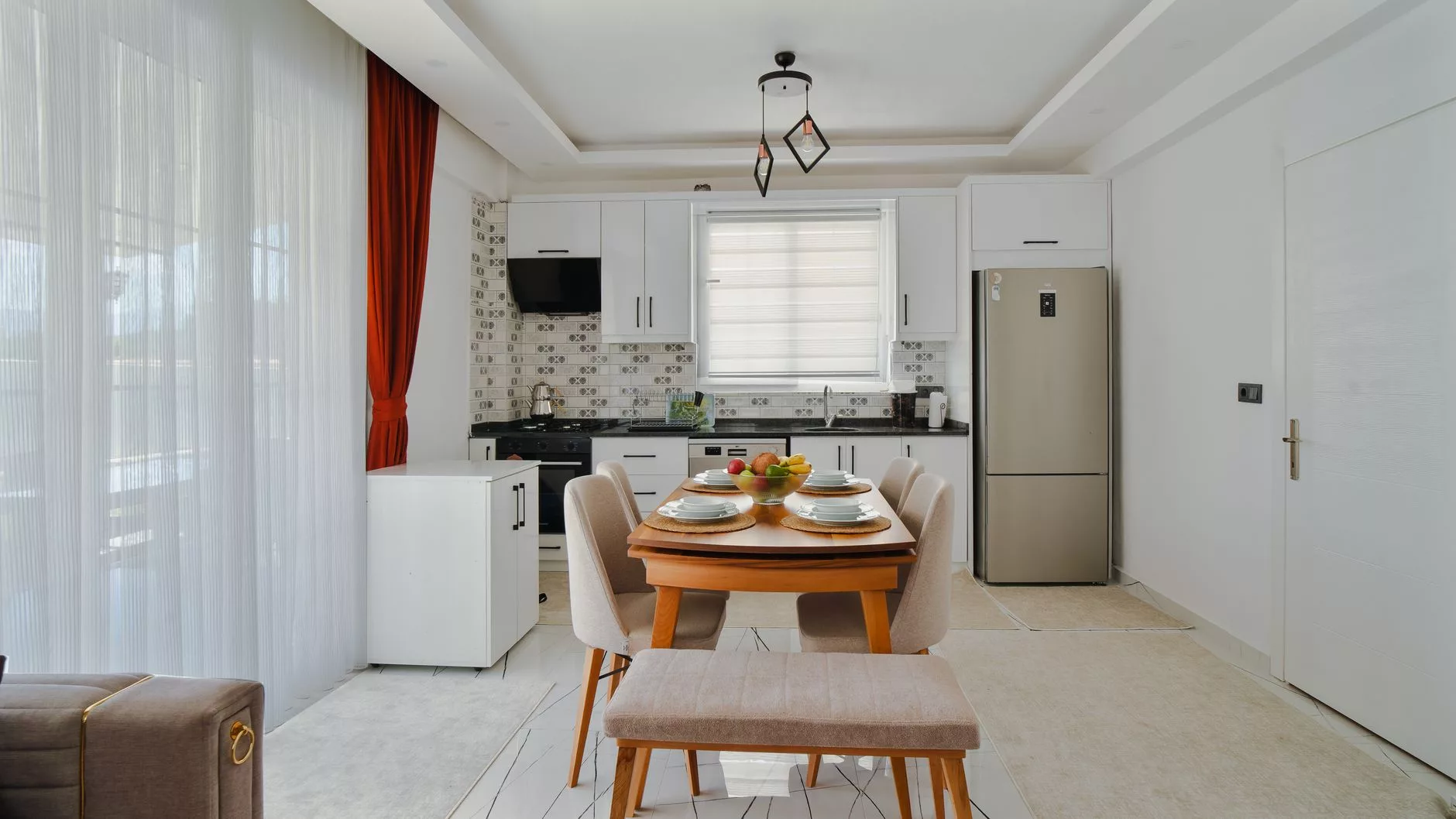 Mutfaklı ve geniş pencereli, bahçeye açılan modern bir apart otel dairesinde kahvaltı hazırlayan aile