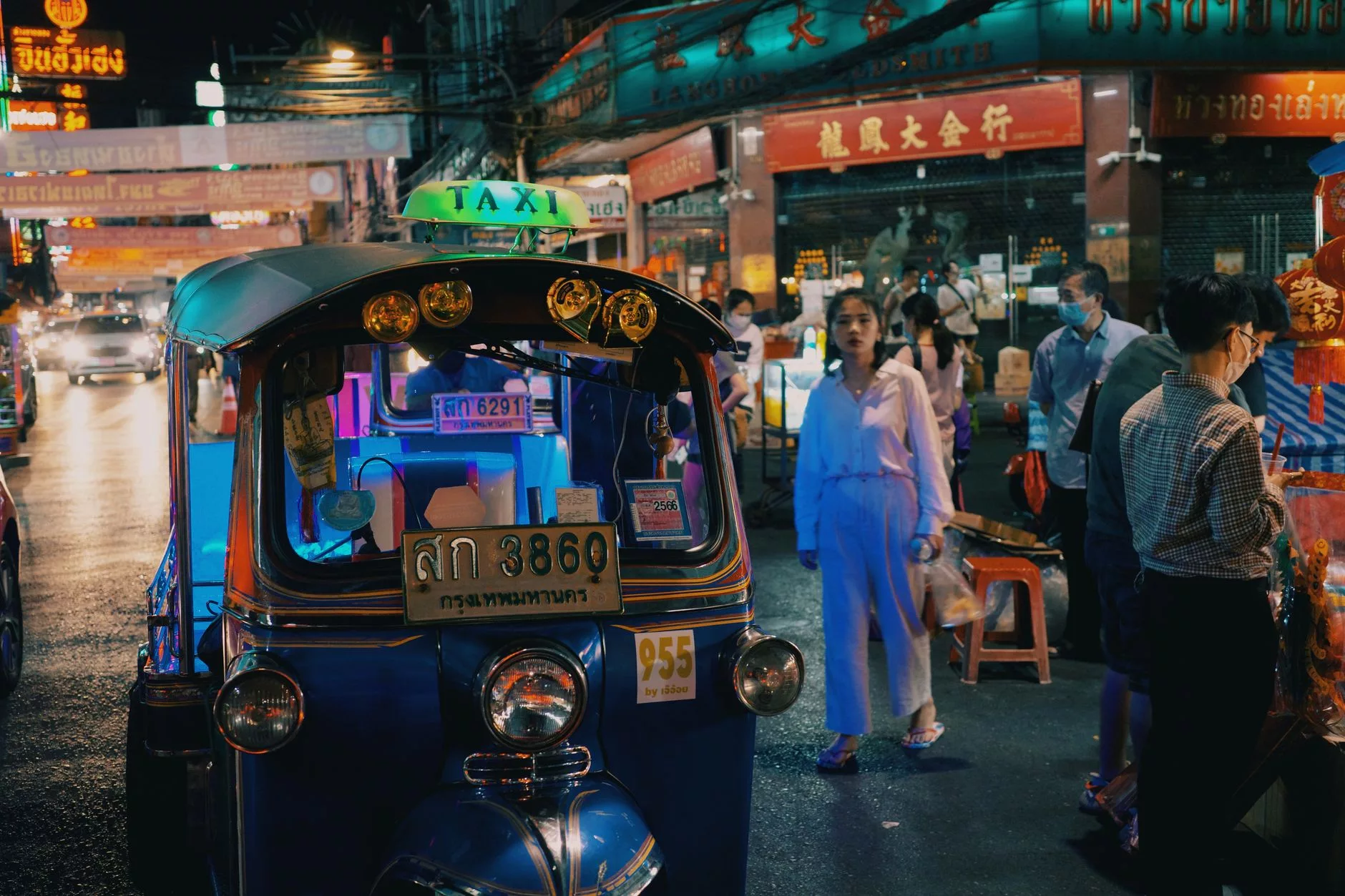 Gece vakti Bangkok caddelerinde neon ışıklar altında ilerleyen taksi